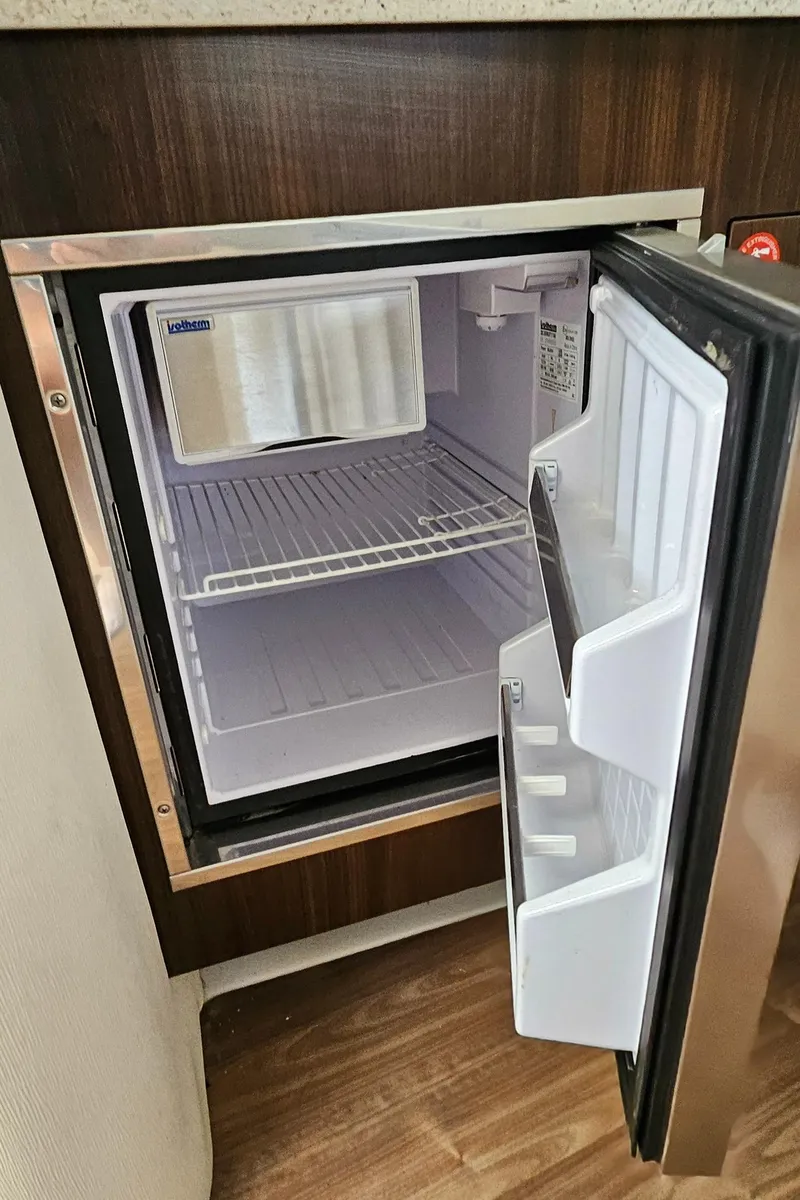 Slide: The Image of Open mini fridge inside 2018 Regal 33 XO boat, showing empty shelves and door compartments. - 31