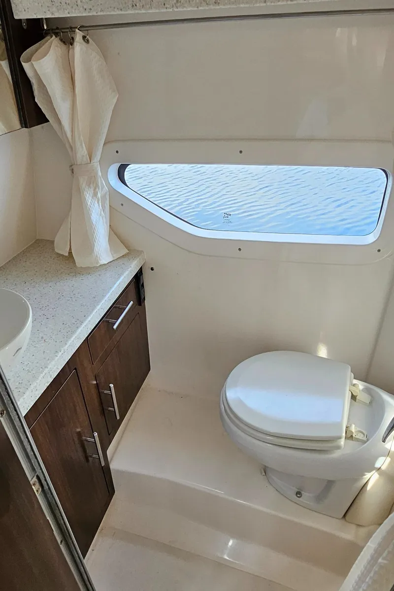 Slide: The Image of 2018 Regal 33 XO boat bathroom with window, toilet, and wooden cabinetry. - 32