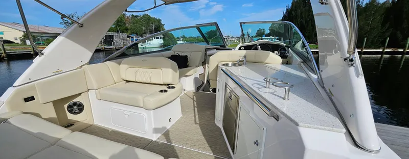 Slide: The Image of 2018 Regal 33 XO boat interior with beige seating and kitchenette, docked by the water. - 4
