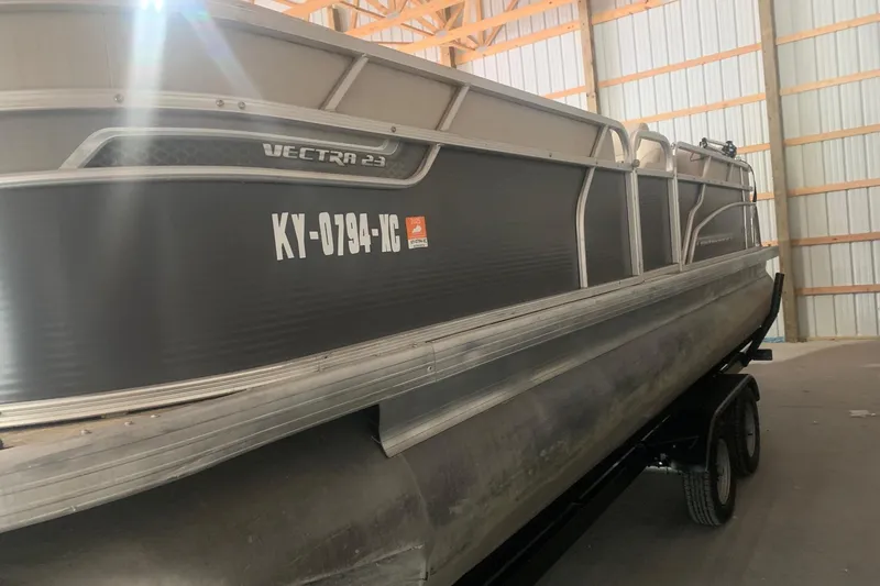 Slide: The Image of 2018 Princecraft Vectra 23 XT pontoon boat in storage, side view with registration number. - 2