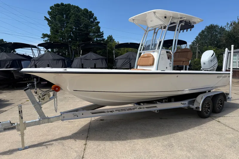 The Image of 2026 Key West 230 Bay Reef boat on trailer, parked outdoors, with trees in background. - 0