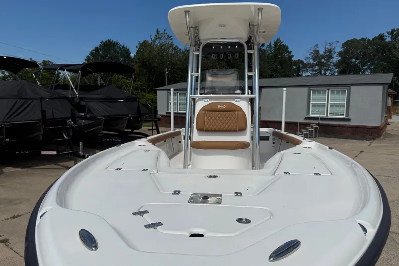 Slide: The Image of 2026 Key West 230 Bay Reef boat with T-top and cushioned seating, parked outdoors. - 7