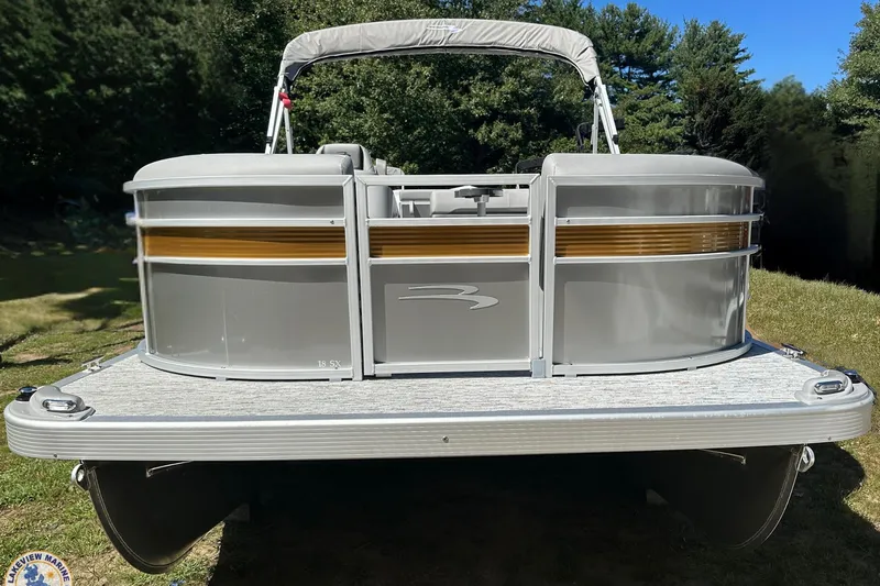 Slide: The Image of 2025 Bennington 18 SXL pontoon boat on grassy area, featuring sleek silver design. - 1