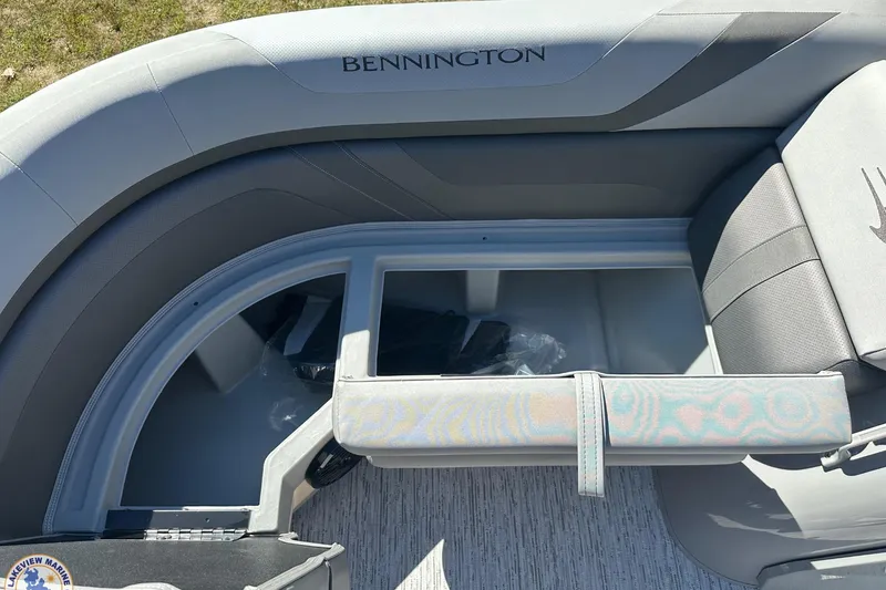 Slide: The Image of 2025 Bennington 18 SXL boat interior with open storage compartment and cushioned seating. - 10