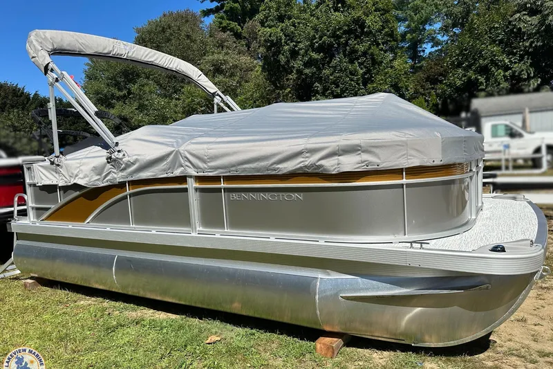 Slide: The Image of 2025 Bennington 18 SXL pontoon boat with cover, parked on grass. - 12