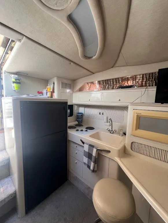 Slide: The Image of Interior of 1996 Sea Ray 400 Sundancer yacht, featuring compact kitchen and modern amenities. - 11