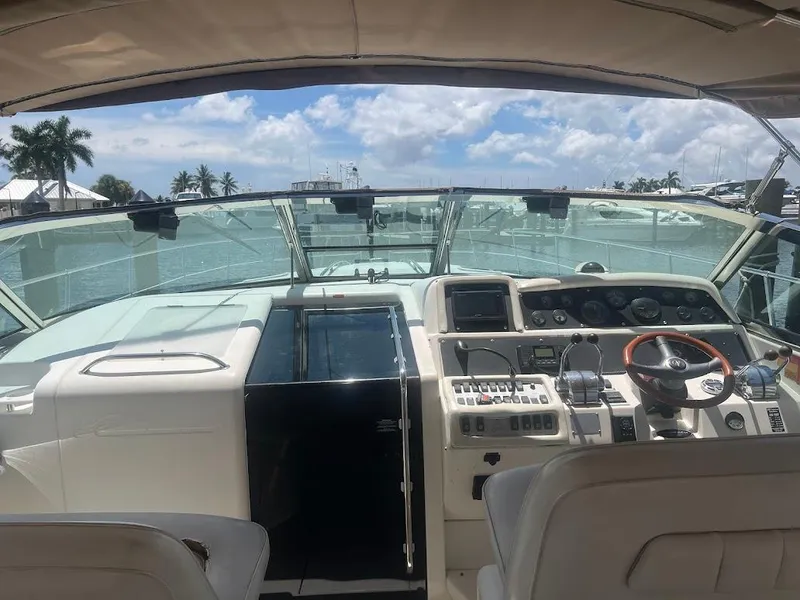 Slide: The Image of 1996 Sea Ray 400 Sundancer yacht cockpit with steering wheel and control panel, docked under blue sky. - 6
