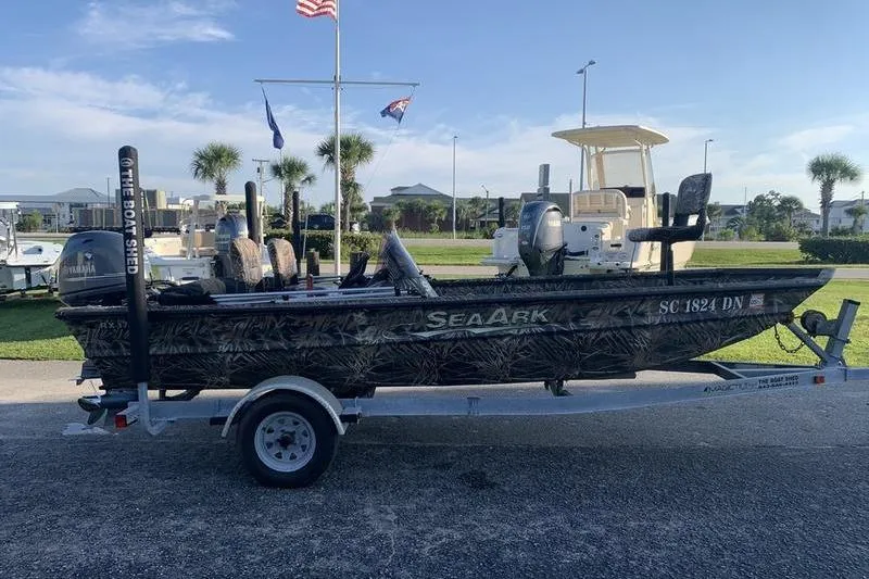 Slide: The Image of 2020 SeaArk RX 170 boat on trailer, parked outdoors with flags in background. - 4