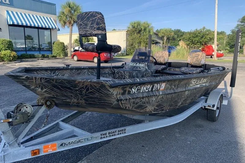 Slide: The Image of 2020 SeaArk RX 170 boat with camouflage design on a trailer in a parking lot. - 7