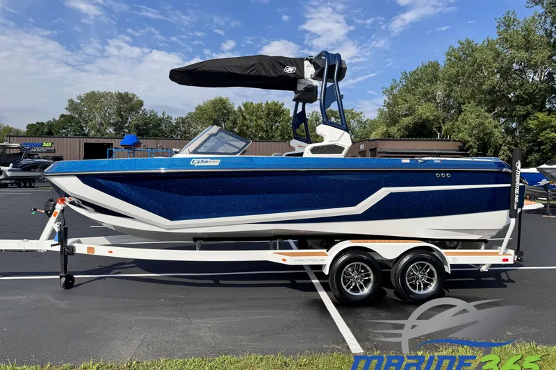 The Image of 2026 Nautique Super Air Nautique GS22 boat on trailer, blue and white design, parked outdoors. - 0
