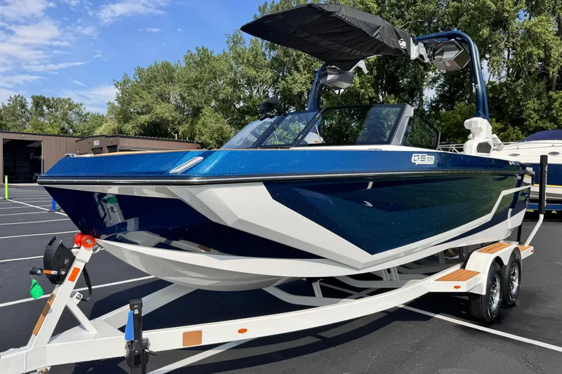 Slide: The Image of 2026 Nautique Super Air Nautique GS22 boat on trailer, blue and white design, parked outdoors. - 1