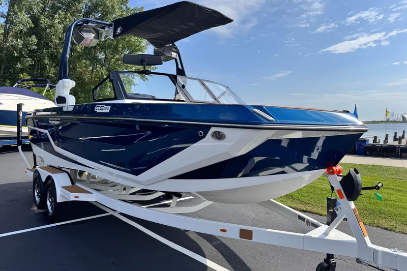 Slide: The Image of 2026 Nautique Super Air Nautique GS22 boat on trailer, parked near a lake. - 2