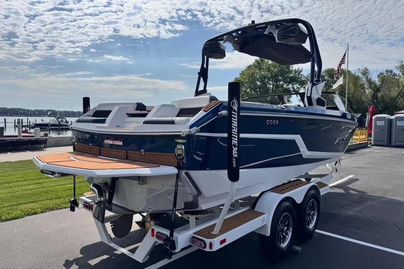 Slide: The Image of 2026 Nautique Super Air Nautique GS22 boat on trailer, parked near a lake under a cloudy sky. - 3