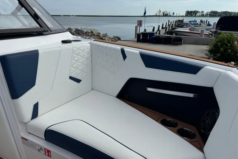 Slide: The Image of 2026 Nautique Super Air Nautique GS22 interior with white and blue seating by a dock. - 33