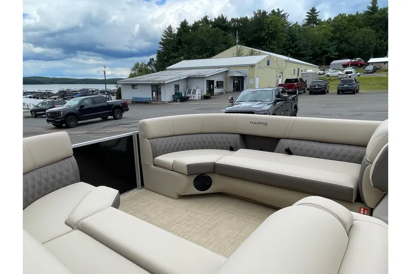 Slide: The Image of 2026 Harris Cruiser 230 pontoon boat with luxurious seating at a lakeside marina. - 9
