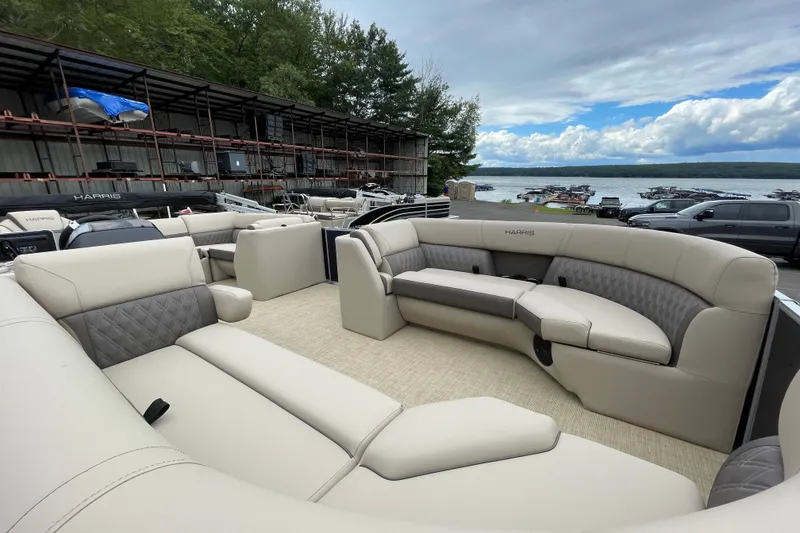 Slide: The Image of 2026 Harris Cruiser 230 pontoon boat with luxurious seating, docked by a scenic lake. - 11