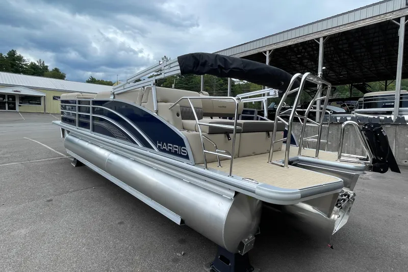 Slide: The Image of 2026 Harris Cruiser 230 pontoon boat with sleek design, parked outdoors under cloudy skies. - 6