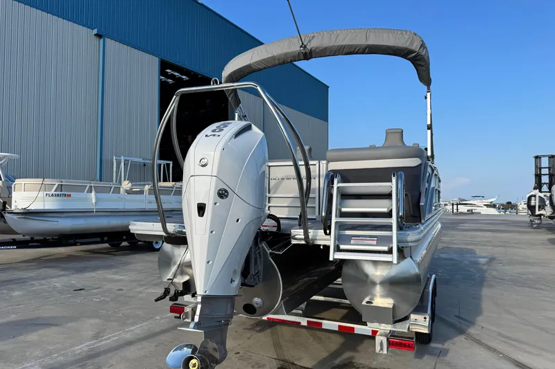 Slide: The Image of 2026 Bennington 24 MFB pontoon boat with outboard motor, docked near a large warehouse. - 5