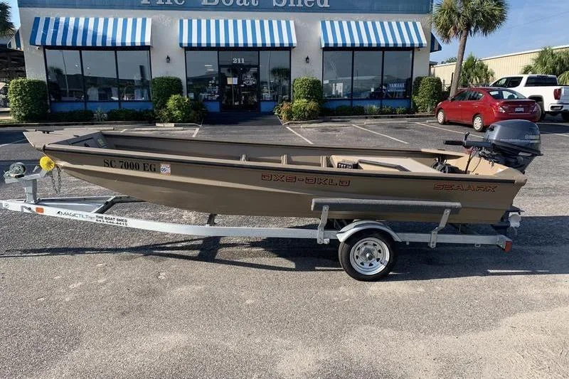 Slide: The Image of 2025 SeaArk DXS 1548 DKLD boat on trailer outside dealership. - 0