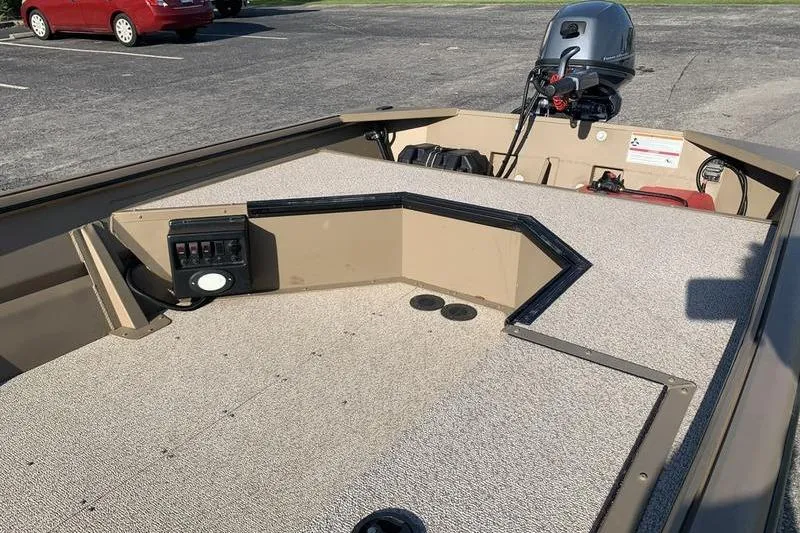 Slide: The Image of 2025 SeaArk DXS 1548 DKLD boat interior with motor, beige deck, and control panel. - 9