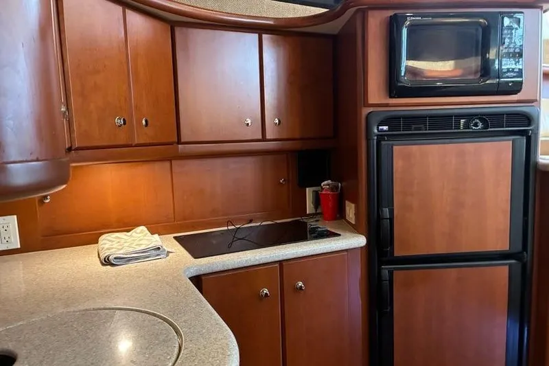 Slide: The Image of 2005 Silverton 34 Convertible yacht kitchen with wooden cabinets, stove, and microwave. - 17