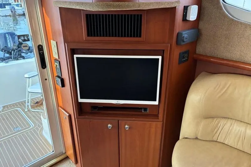 Slide: The Image of Interior of 2005 Silverton 34 Convertible yacht with TV and beige seating. - 28
