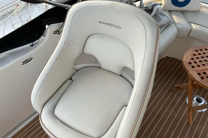 Slide: The Image of Captain's chair on 2005 Silverton 34 Convertible yacht, featuring white upholstery and wooden deck. - 5