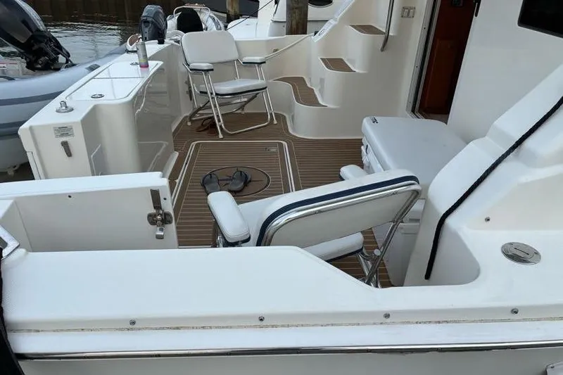 Slide: The Image of 2005 Silverton 34 Convertible boat deck with chairs and steps, docked by water. - 8