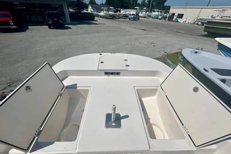 Slide: The Image of 2025 Carolina Skiff 21 LS boat with open storage compartments in a marina setting. - 4