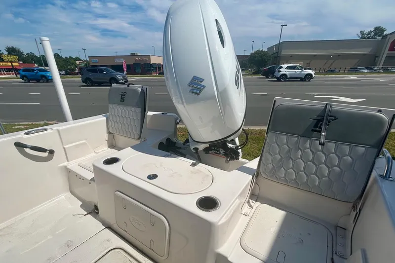 Slide: The Image of 2025 Carolina Skiff 21 LS boat interior with Suzuki outboard motor, parked near a road. - 8