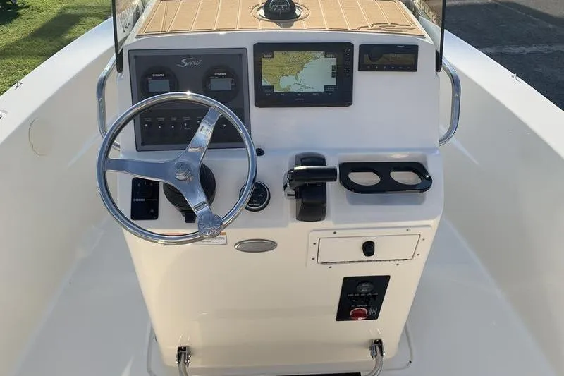 Slide: The Image of 2026 Scout 195 Sportfish boat console with steering wheel, navigation display, and controls. - 14