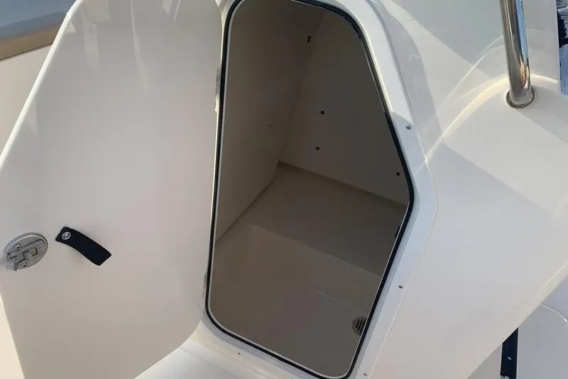 Slide: The Image of 2026 Scout 195 Sportfish boat storage compartment with open door, showcasing interior space. - 20