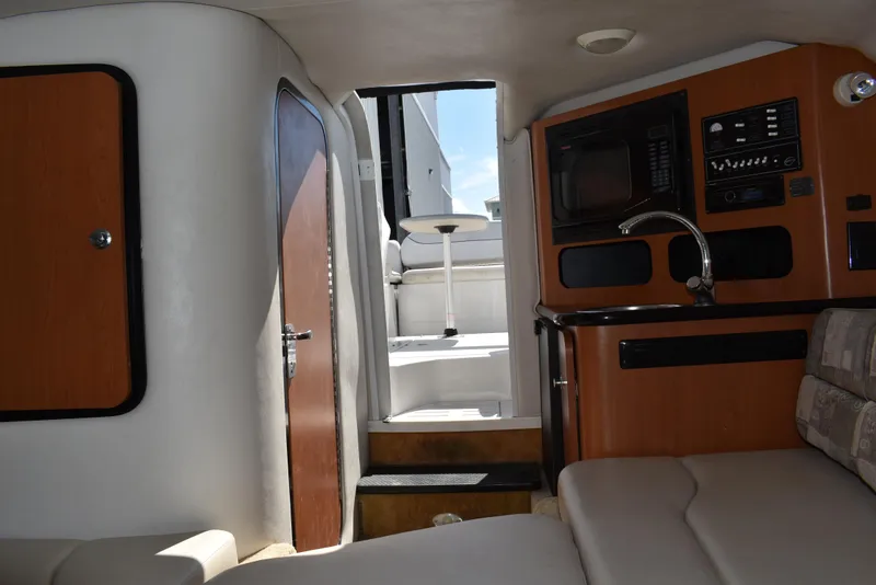 Slide: The Image of Interior of 2005 Crownline 275 CCR boat, featuring cozy seating and compact kitchenette. - 33