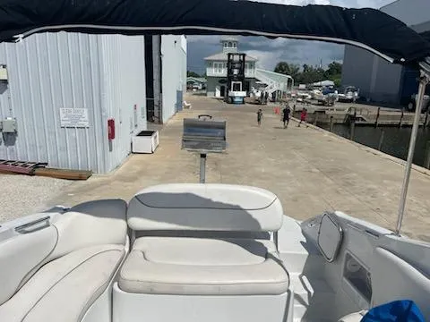 Slide: The Image of 2005 Crownline 275 CCR boat interior at marina dock, featuring white seating and canopy. - 40