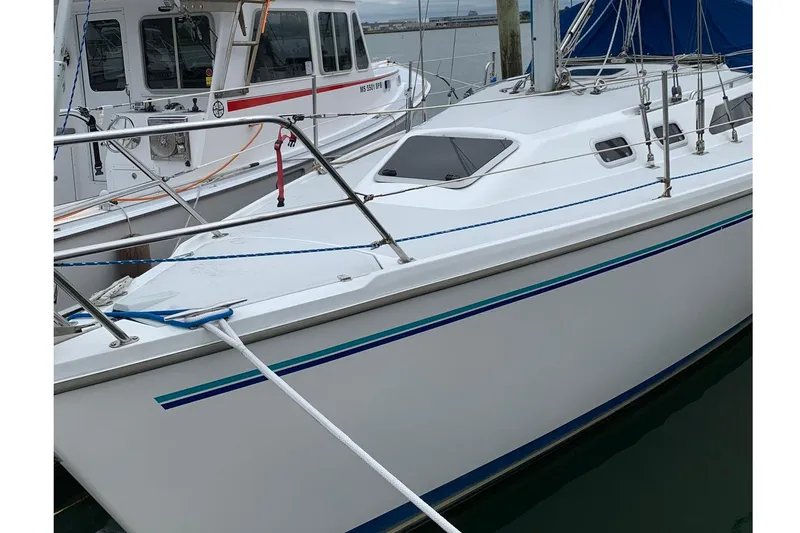 Slide: The Image of 1998 Catalina 320 sailboat docked at marina, featuring sleek white hull and blue accents. - 27
