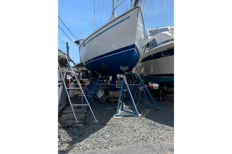 Slide: The Image of 1998 Catalina 320 sailboat on stands in a boatyard, under clear blue sky. - 8