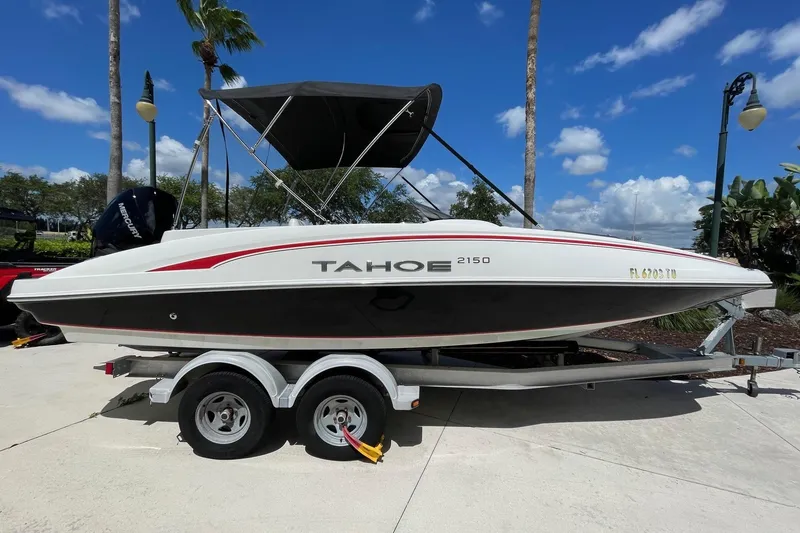 The Image of 2024 Tahoe 2150 OB boat on trailer, parked outdoors under a clear blue sky. - 0