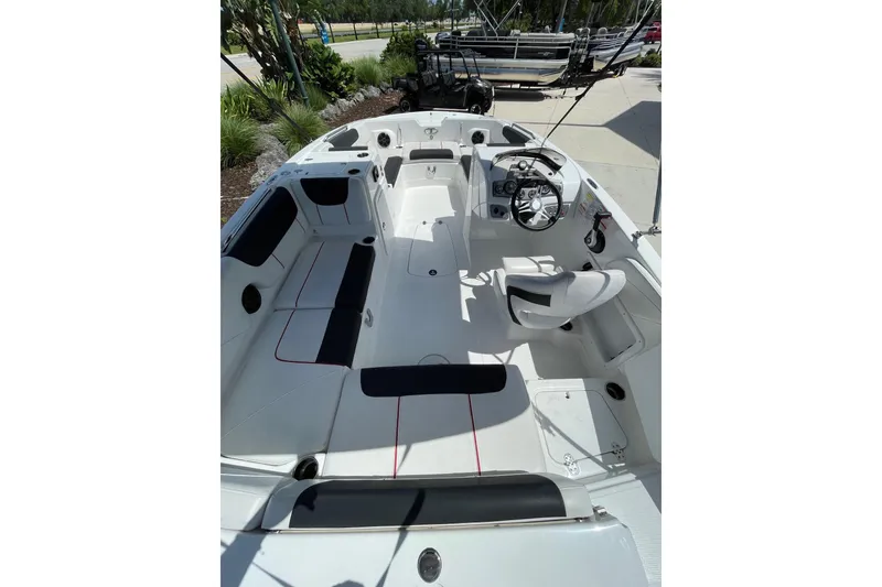 Slide: The Image of 2024 Tahoe 2150 OB boat interior with seating and steering wheel, docked outdoors. - 1