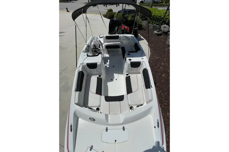 Slide: The Image of 2024 Tahoe 2150 OB boat with spacious seating and canopy, docked outdoors. - 3