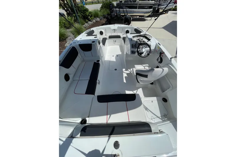 Slide: The Image of 2024 Tahoe 2150 OB boat interior with seating and steering wheel, docked outdoors. - 5