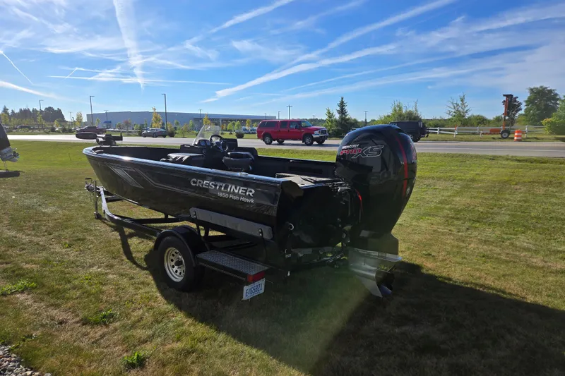 Slide: The Image of 2021 Crestliner 1850 Fish Hawk SC JS boat on trailer, parked on grass under blue sky. - 5