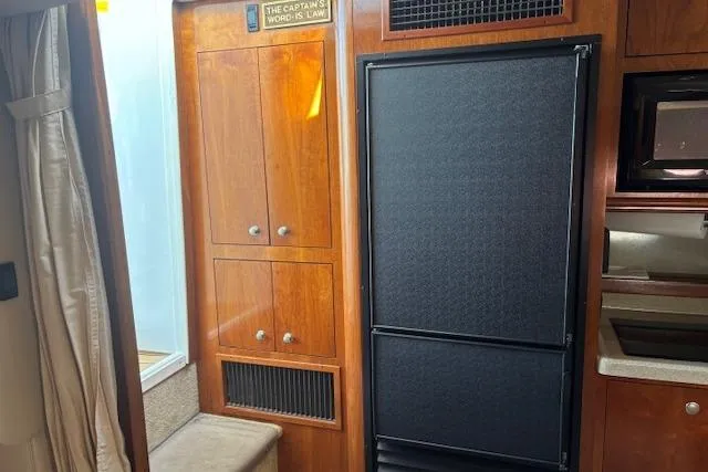 Slide: The Image of 2004 Cruisers Yachts 370 Express interior with wood cabinetry and black refrigerator. - 4