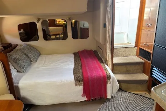 Slide: The Image of 2004 Cruisers Yachts 370 Express cabin interior with bed, mirrors, and stairs. - 9