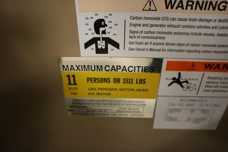 Slide: The Image of Warning labels on a 2018 Lowe 230 Retreat WT boat, indicating maximum capacity and carbon monoxide risks. - 24