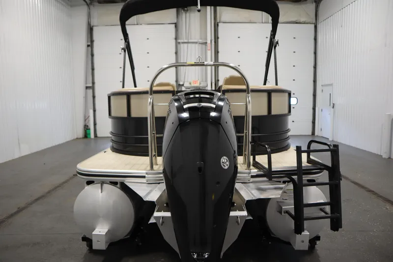 Slide: The Image of 2018 Lowe 230 Retreat WT pontoon boat in indoor storage, rear view with motor and ladder. - 5