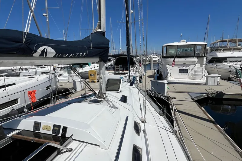 Slide: The Image of 1988 Hunter 37.5 sailboat docked at marina, surrounded by other boats under clear blue sky. - 10