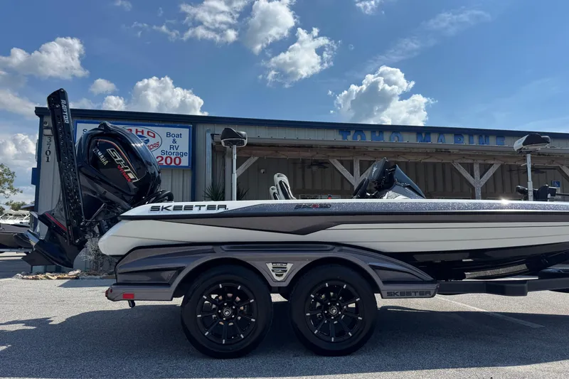 Slide: The Image of 2026 Skeeter FXR20 FLEX boat parked outside a marine store under a blue sky. - 2