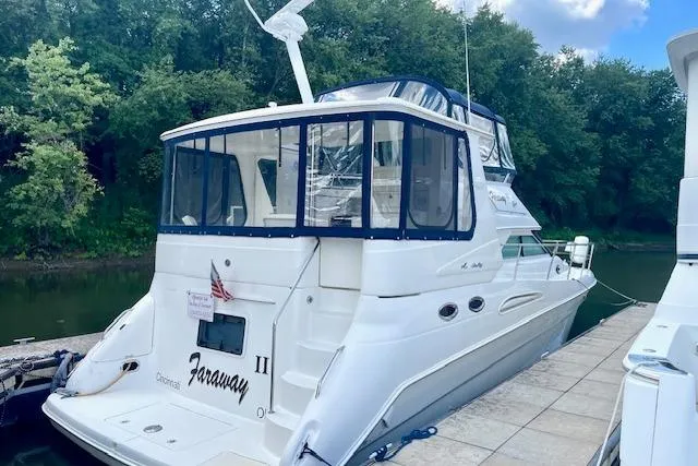 The Image of 2001 Sea Ray 420 Aft Cabin yacht docked by lush greenery. - 1