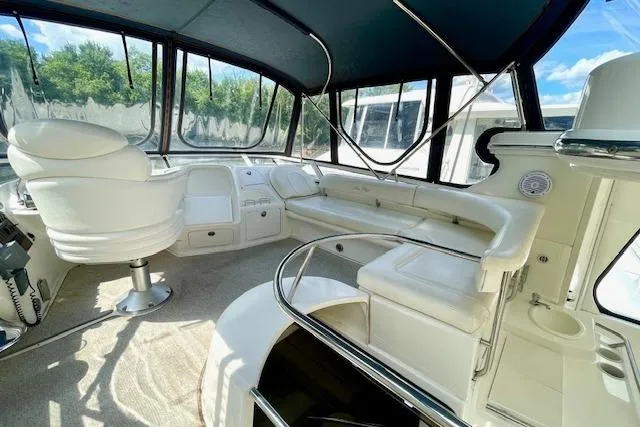 Slide: The Image of 2001 Sea Ray 420 Aft Cabin interior with white seating and helm, featuring panoramic windows. - 11