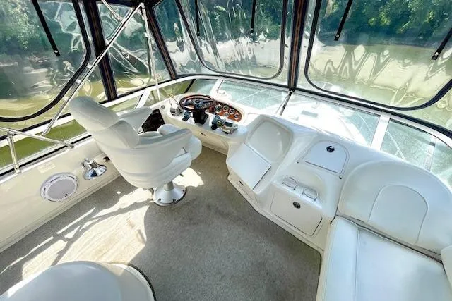 Slide: The Image of 2001 Sea Ray 420 Aft Cabin yacht interior with helm, white seating, and panoramic windows. - 12